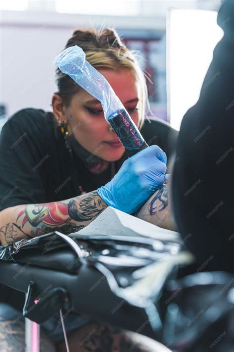 Focused Female Tattoo Artist Drawing A Tattoo On Her Client Leg Tattoo